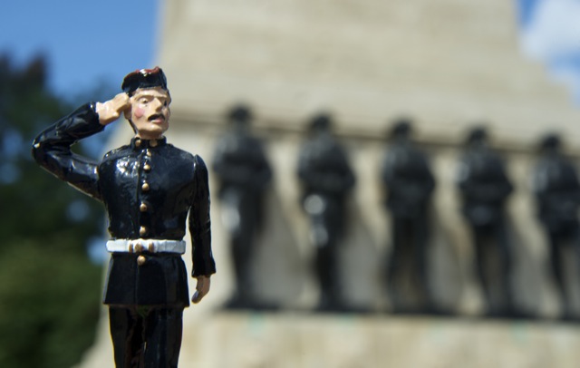 Lead toy soldier saluting with the Guards Memorial, London, in the background